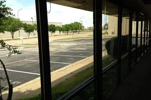 Interior view along a long glazed commercial corridor onto a parking lot, Lubbock